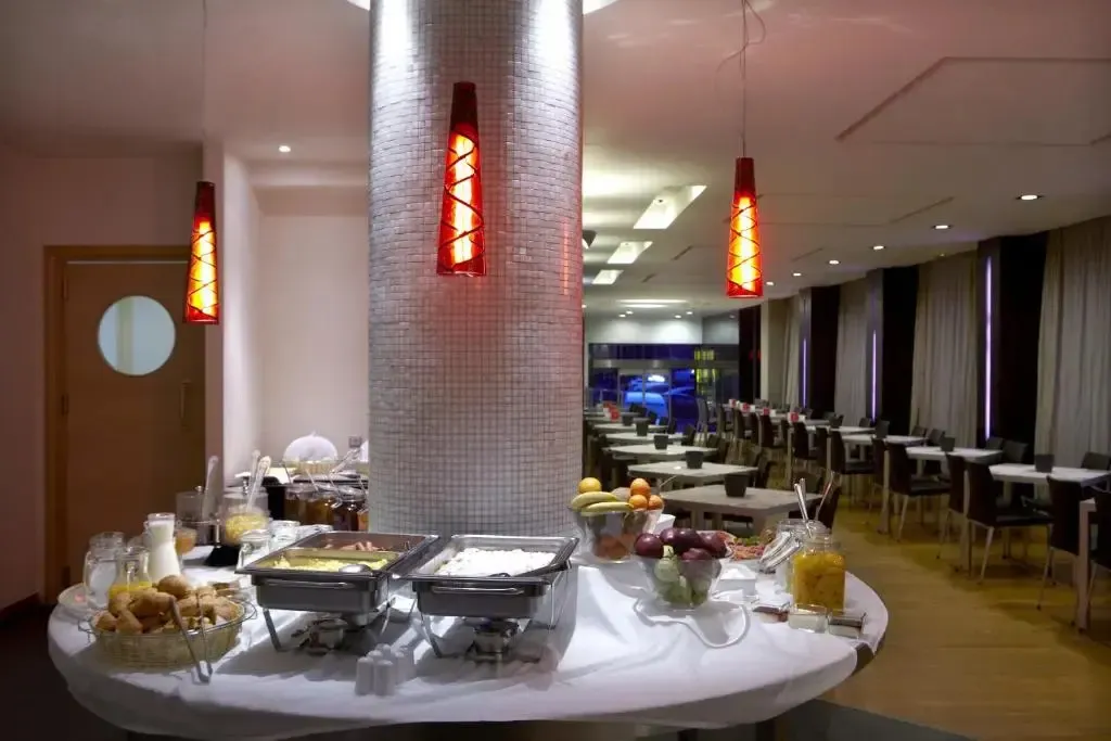 Un buffet propose des viennoiseries, des fruits et des boissons dans une salle lumineuse.