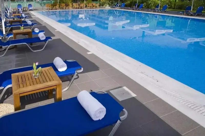 Transats bleus alignés au bord d'une piscine ensoleillée.