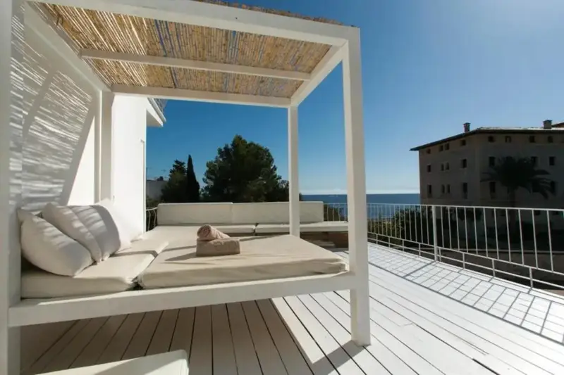 Espace de détente extérieur avec coussins et vue sur la mer.