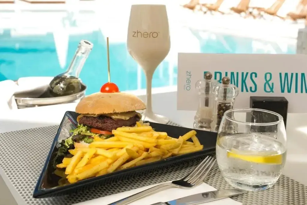 Un hamburger et des frites sont servis sur une table près d'une piscine.