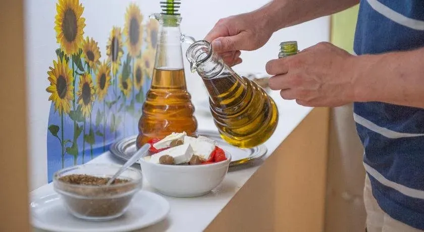 Une personne verse de l'huile d'olive sur une salade.