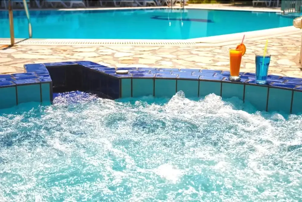 Jacuzzi avec cocktails au bord d'une piscine ensoleillée.