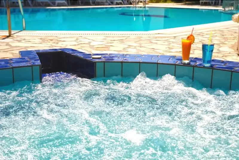 Jacuzzi avec cocktails au bord d'une piscine ensoleillée.