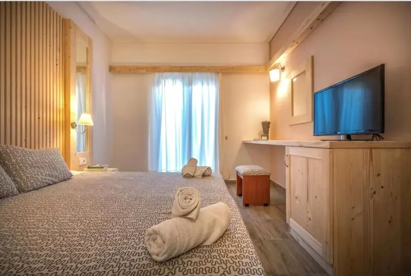 Une chambre lumineuse avec un lit fait et un meuble télévision.