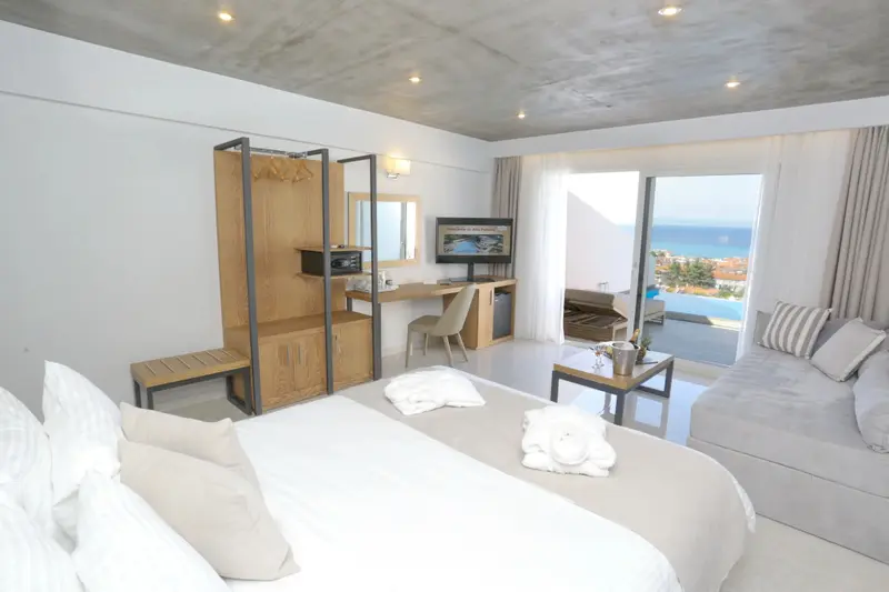 Une chambre lumineuse avec un grand lit et un canapé face à une baie vitrée.