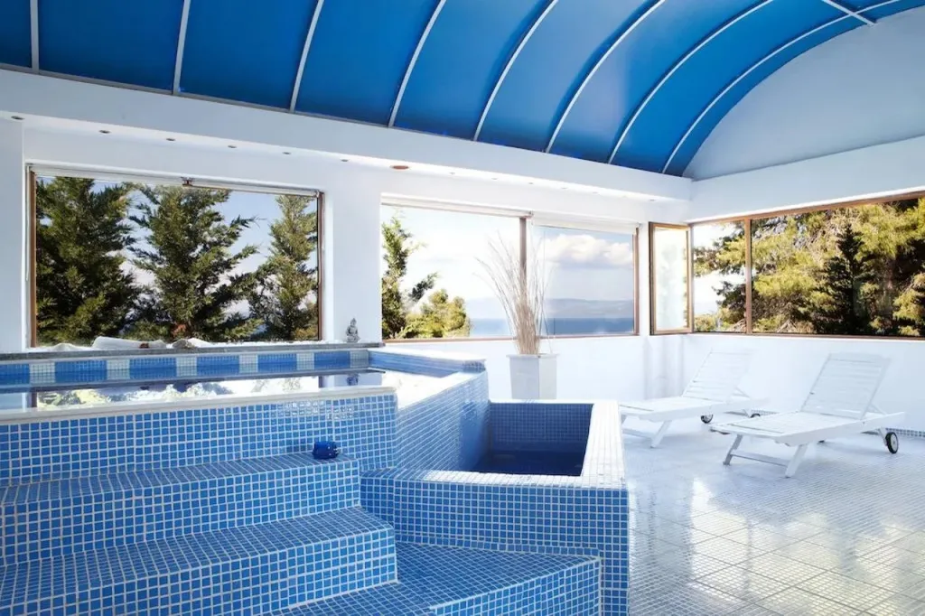 Espace de détente intérieur avec piscine et vue sur la mer.