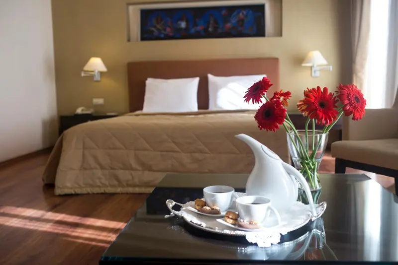 Une table basse avec un service à thé et des pâtisseries se trouve devant un lit confortable dans une chambre.