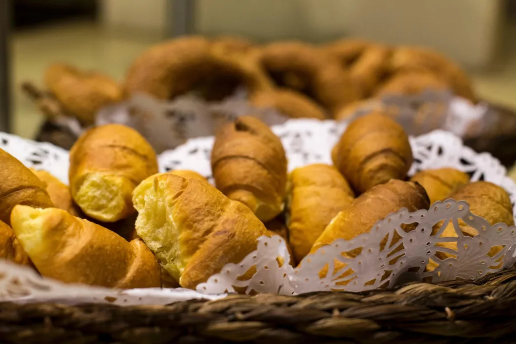 Des viennoiseries dorées sont présentées dans un panier en osier.