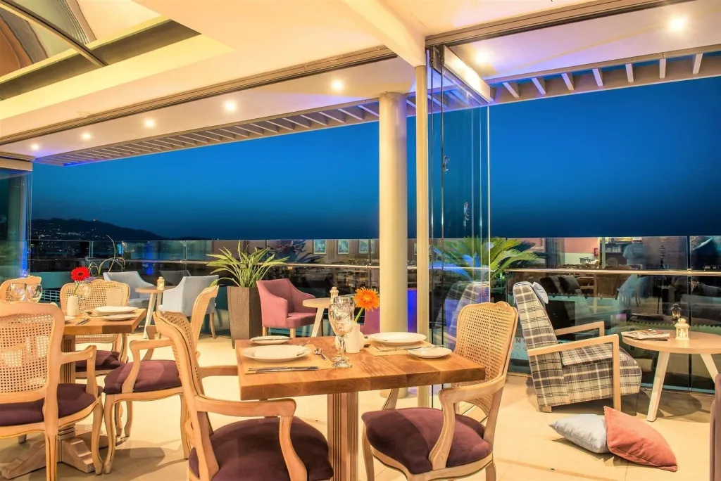 Tables dressées en extérieur avec vue sur un paysage urbain illuminé au crépuscule.