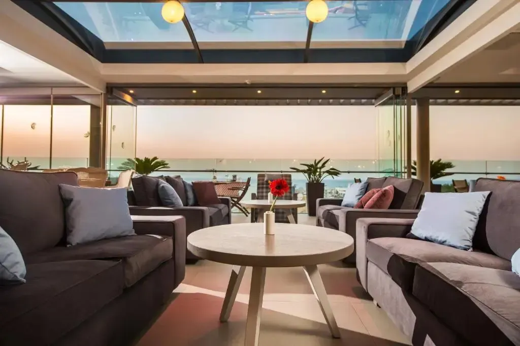 Un espace de détente intérieur avec des canapés et une vue sur la mer au coucher du soleil.