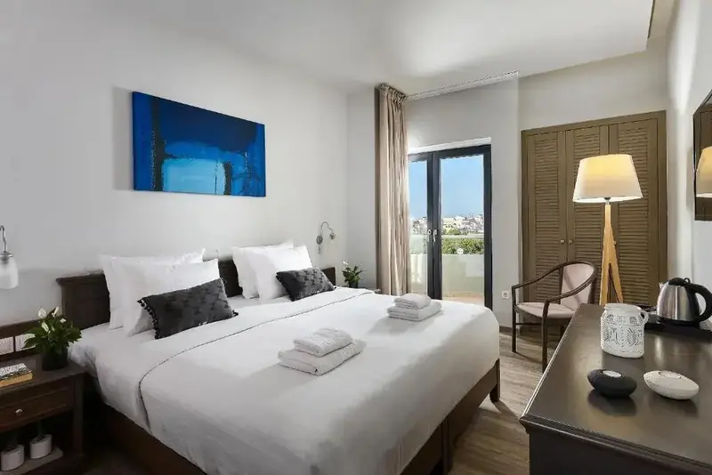 Une chambre lumineuse avec un grand lit et un accès à un balcon.