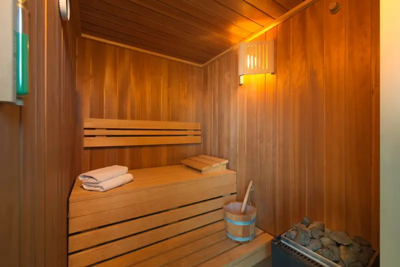 Intérieur chaleureux d'un sauna en bois avec des serviettes pliées sur un banc.