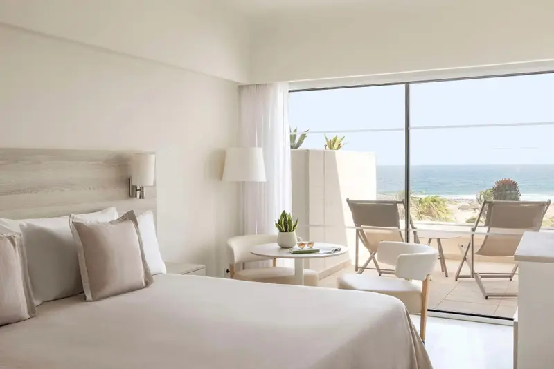 Une chambre lumineuse s'ouvre sur une terrasse avec vue sur la mer.