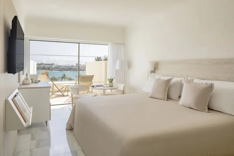 Une chambre lumineuse avec un grand lit et une vue sur la mer.