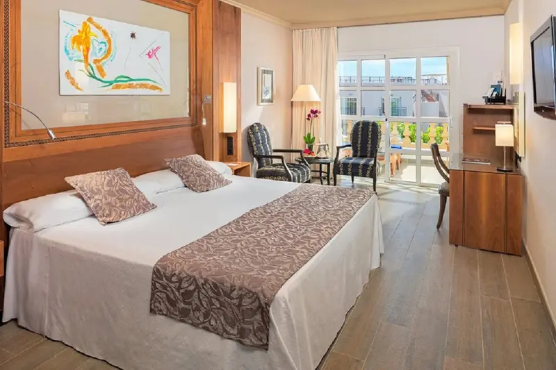 Une chambre lumineuse avec un grand lit et deux fauteuils.