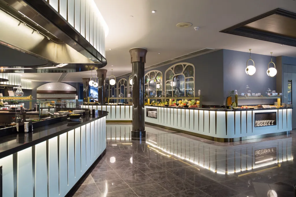 Un buffet propose une grande variété de plats et de desserts dans une salle lumineuse.
