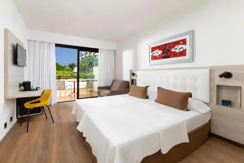 Une chambre lumineuse avec un grand lit et un accès à un balcon.