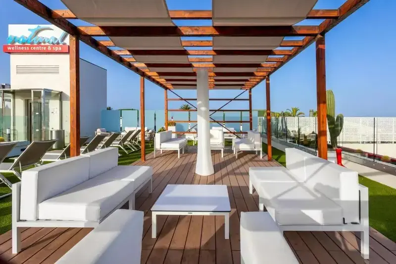 Espace de détente extérieur avec mobilier blanc sous une pergola.