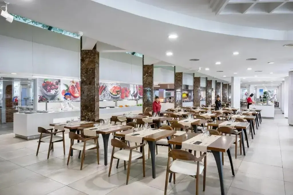 Une salle lumineuse et spacieuse est aménagée avec des tables et des chaises pour les repas.