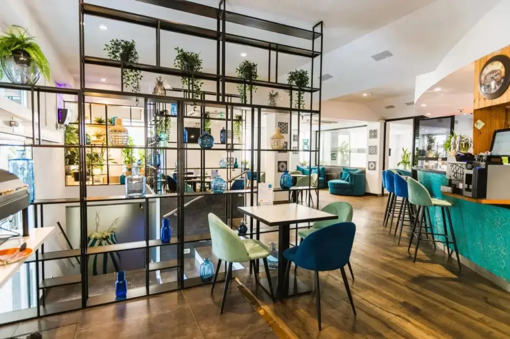 Une salle lumineuse avec des tables, des chaises et un comptoir turquoise.