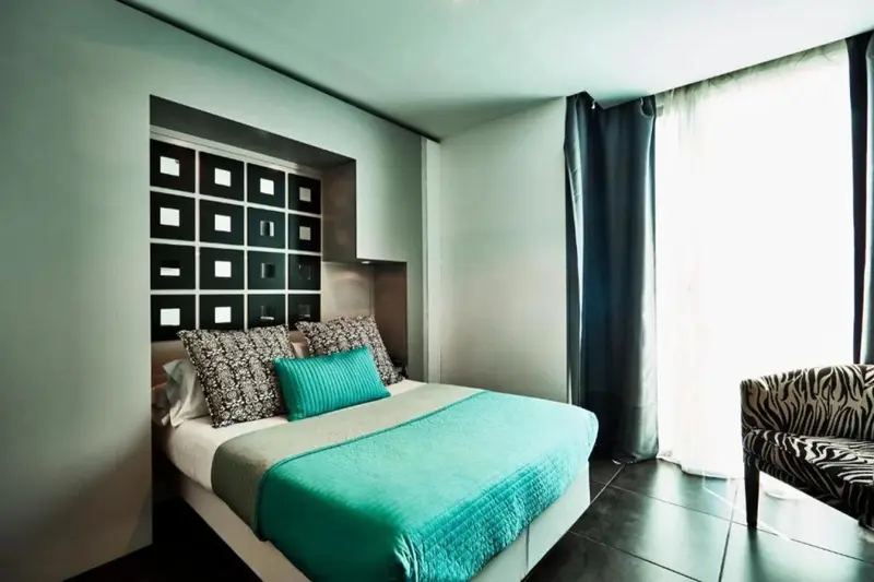 Une chambre moderne avec un lit turquoise et un mur décoratif.