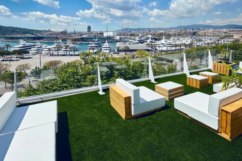 Espace de détente extérieur avec mobilier blanc et vue sur un port de plaisance.