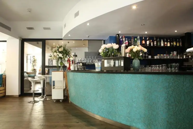 Un comptoir de bar turquoise est présenté dans un espace lumineux et moderne.