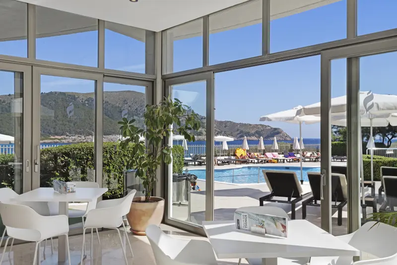 Une salle lumineuse donne sur une piscine et la mer.