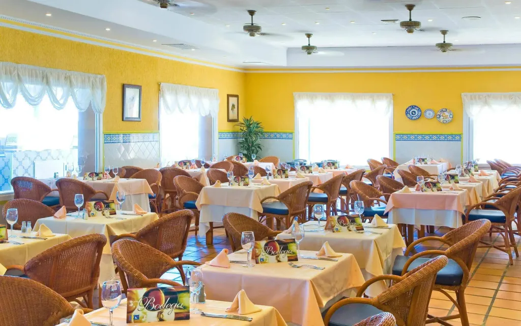 Une salle lumineuse et spacieuse est aménagée avec des tables dressées pour le service.