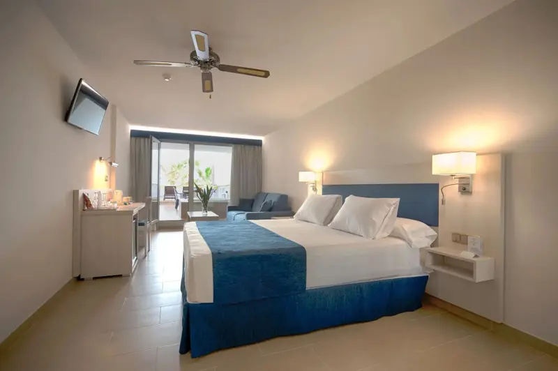 Une chambre lumineuse avec un grand lit et un accès à une terrasse.