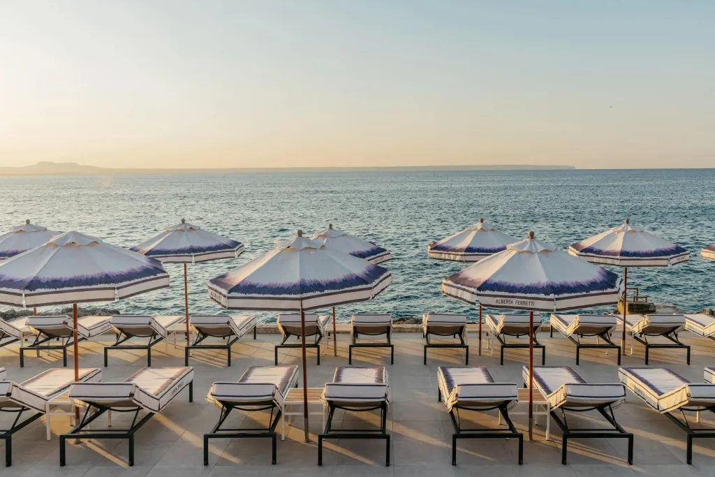 Transats et parasols sur une terrasse ensoleillée face à la mer.