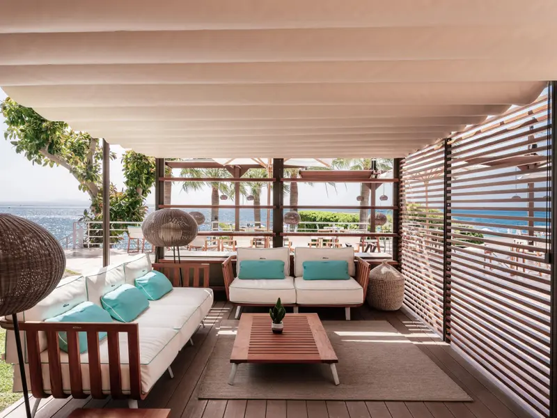 Espace de détente extérieur avec canapés et vue sur la mer.