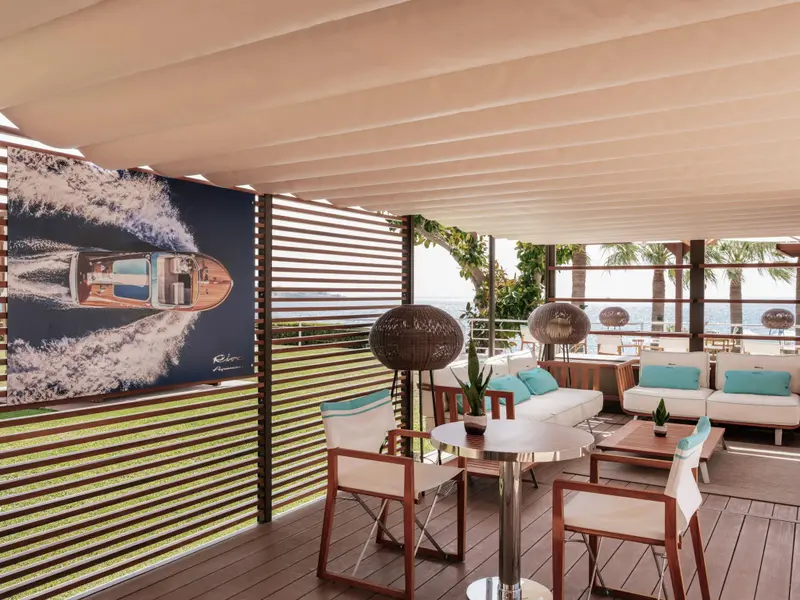 Espace de détente extérieur avec mobilier contemporain et une grande photographie d'un bateau à moteur.