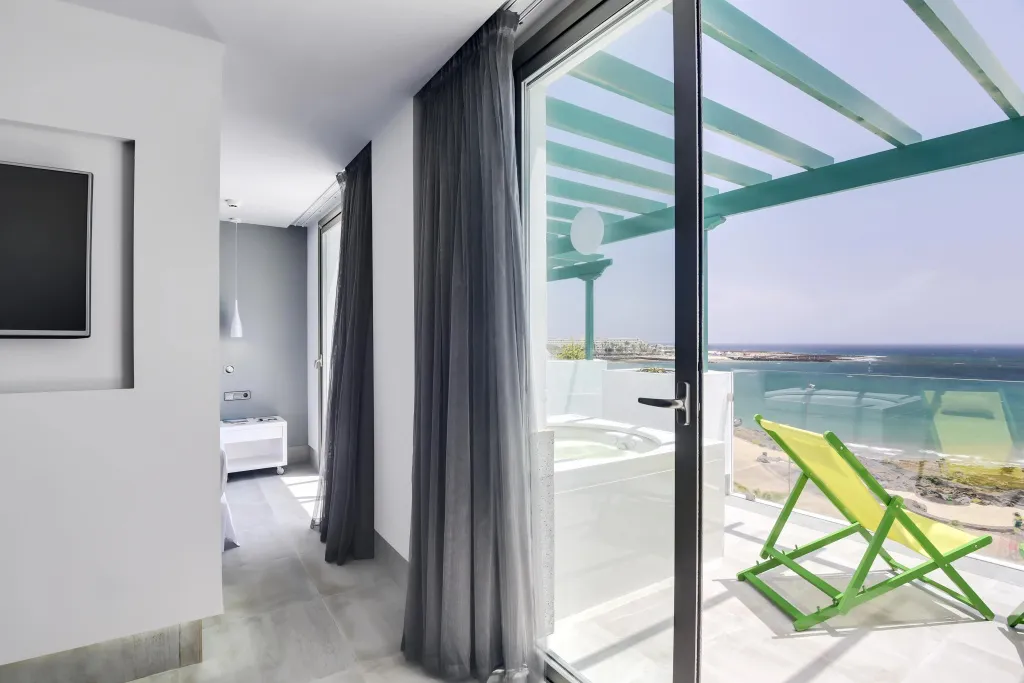 Une chambre lumineuse s'ouvre sur une terrasse avec vue sur la mer.