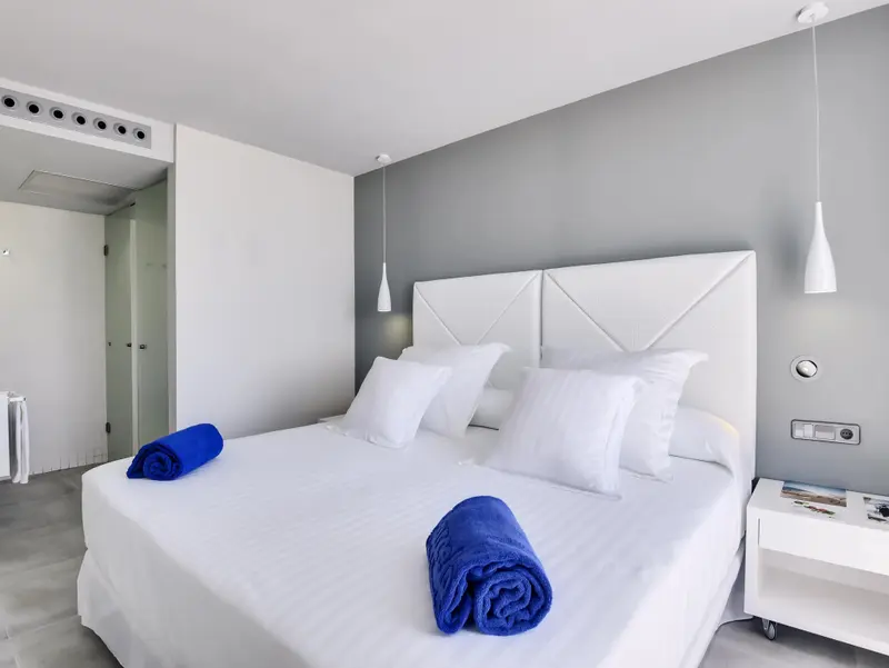 Une chambre lumineuse avec un grand lit recouvert de linge blanc et des oreillers moelleux.