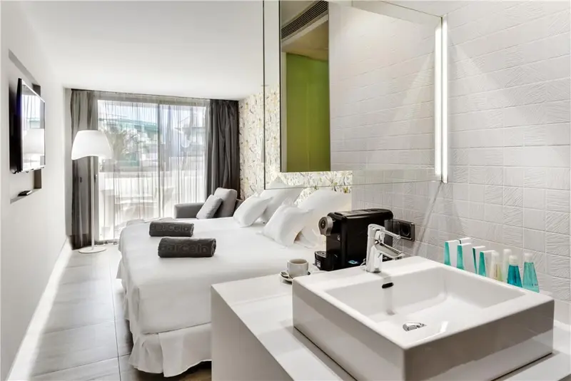 Une chambre lumineuse avec un grand lit et un lavabo moderne.
