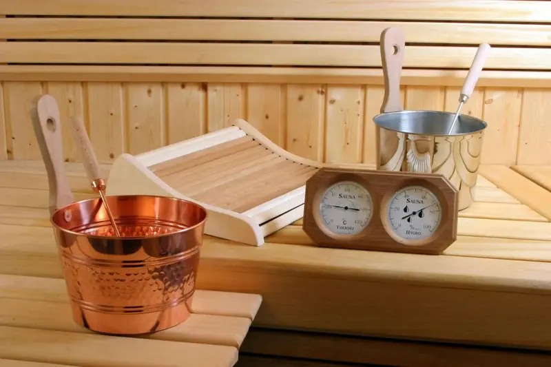 Intérieur d'un sauna en bois avec seaux, louche et thermomètre.
