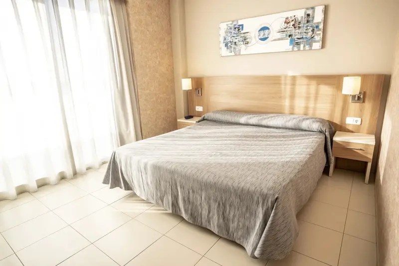Une chambre lumineuse avec un grand lit recouvert d'une couverture.