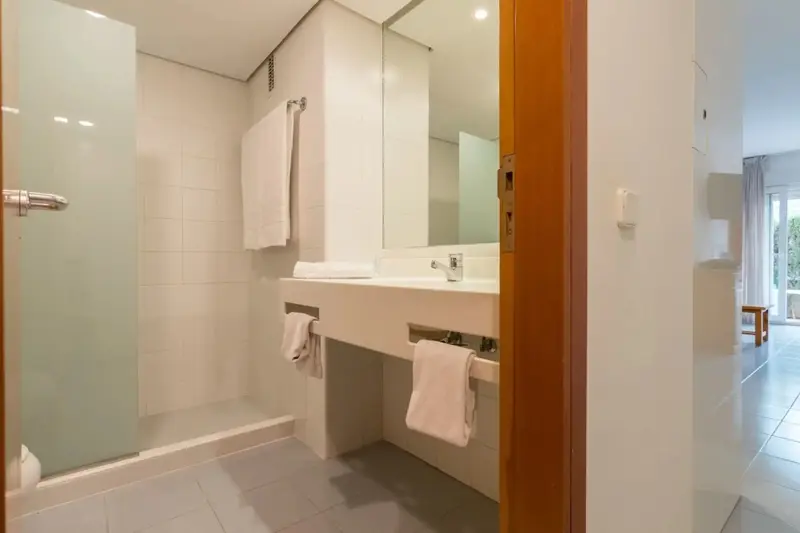 Une salle de bain lumineuse avec une douche vitrée et un grand miroir au-dessus du plan vasque.