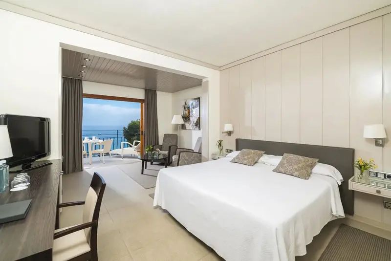 Une chambre lumineuse avec un grand lit et un accès à une terrasse avec vue sur la mer.