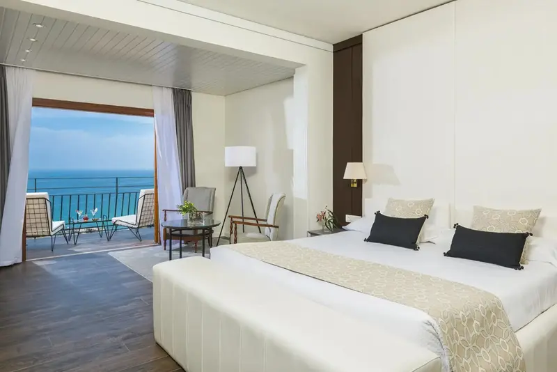 Une chambre lumineuse avec un grand lit donnant sur la mer.