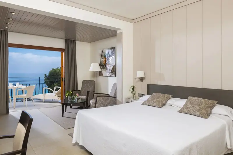 Une chambre lumineuse avec un grand lit blanc et une vue sur la mer.