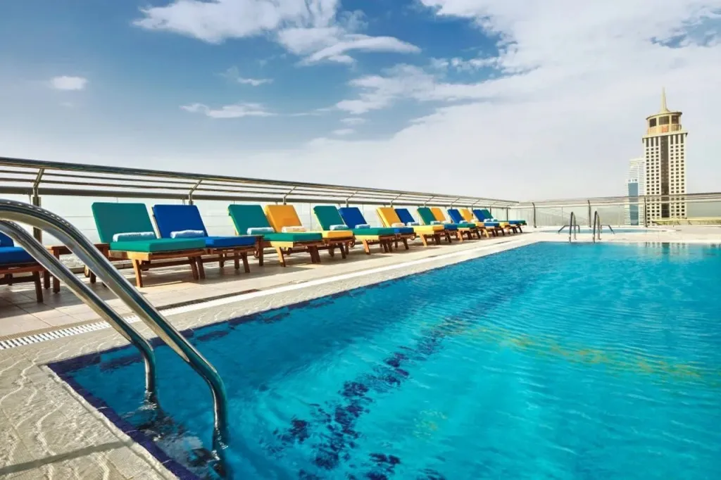 Transats colorés alignés au bord d'une piscine ensoleillée.