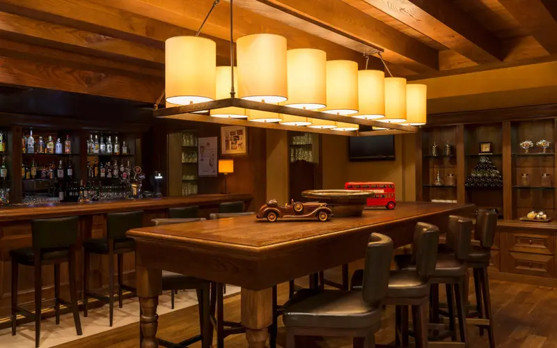 Un long comptoir en bois est entouré de tabourets hauts dans un bar chaleureux et élégant.