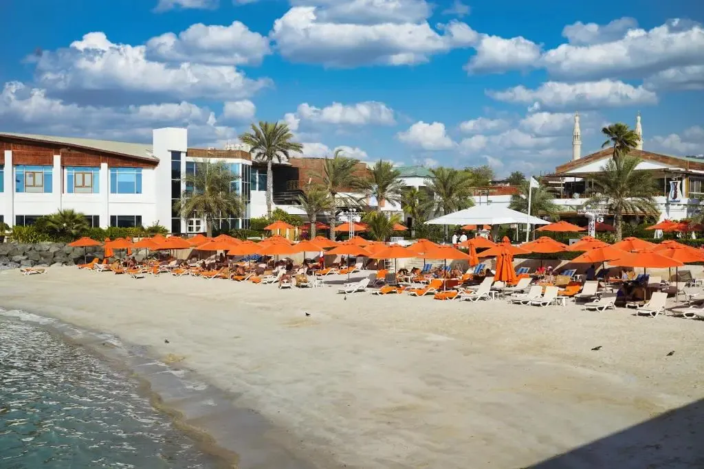 Plage de sable fin avec transats et parasols face à la mer.
