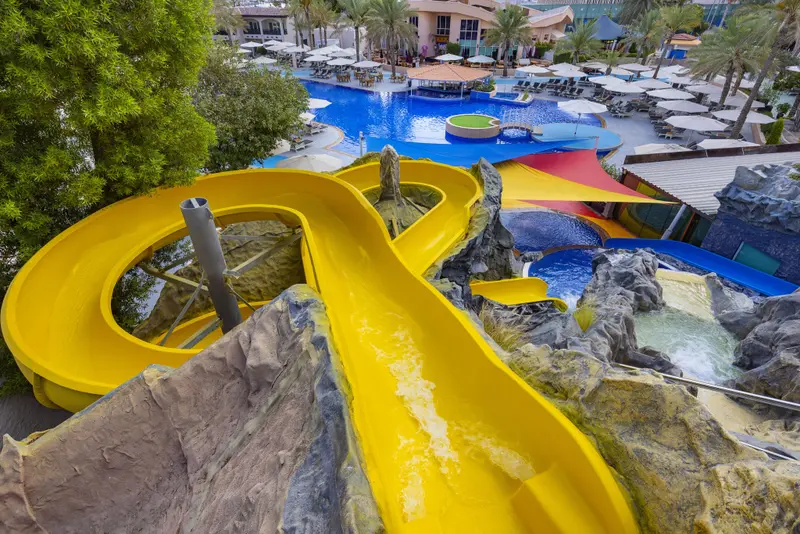 Toboggan aquatique jaune descendant vers une piscine ensoleillée.
