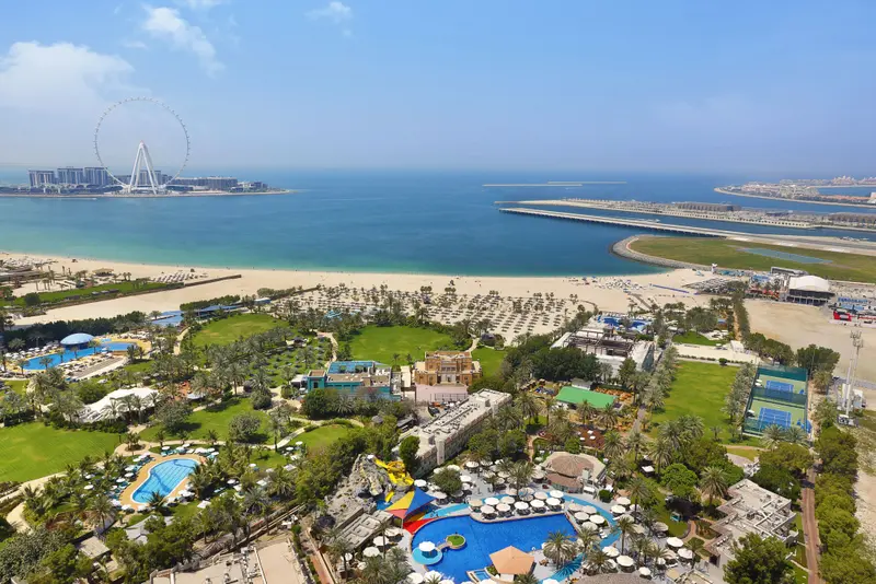 Vue aérienne d'un complexe hôtelier avec piscines et plage.