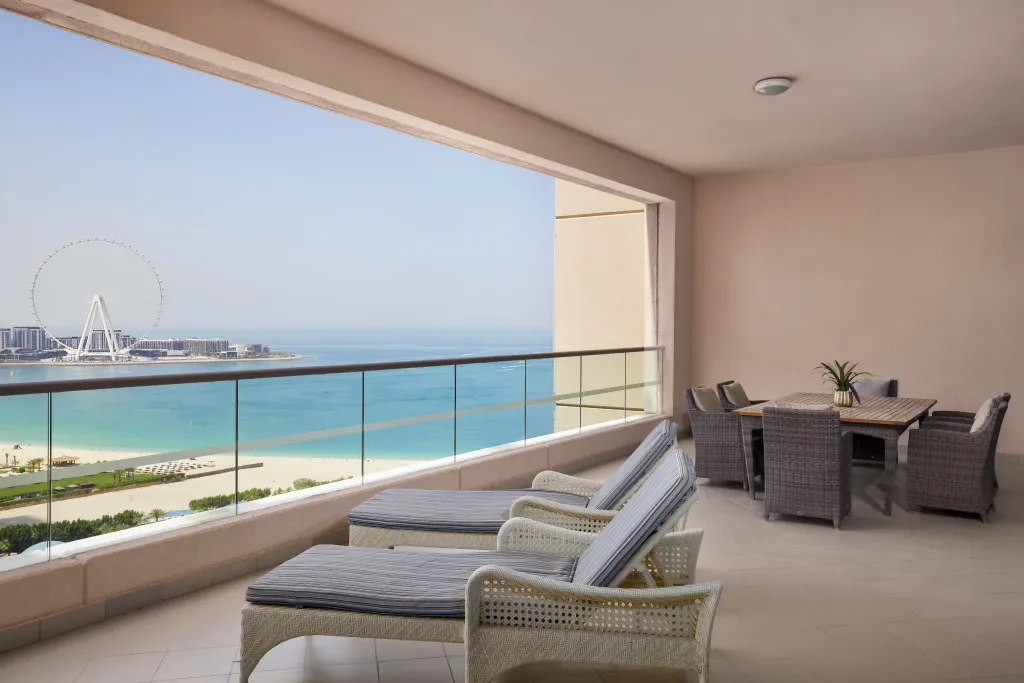 Terrasse aménagée avec transats et table à manger offrant une vue sur la mer.