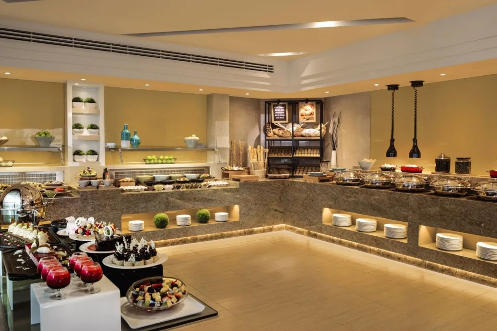 Un buffet propose une grande variété de plats et de desserts dans une salle lumineuse.