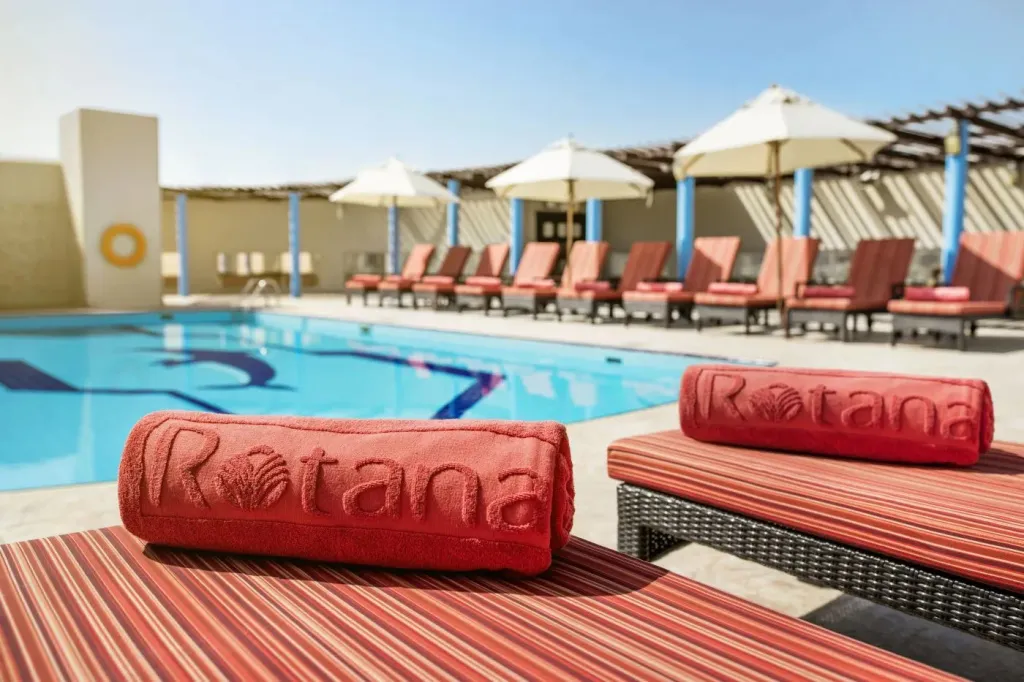 Transats rouges au bord d'une piscine ensoleillée.